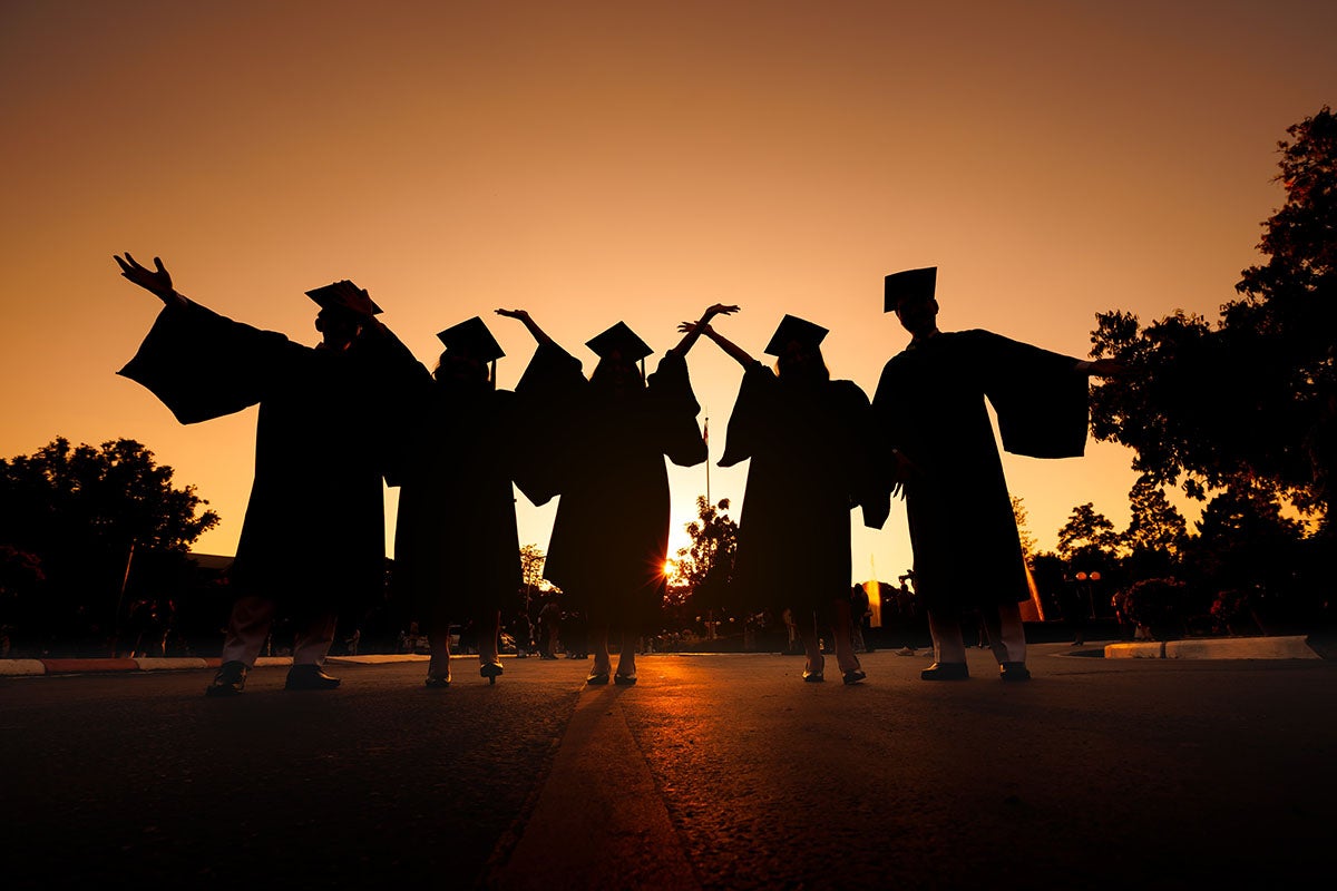 Graduates celebrating at sunset.