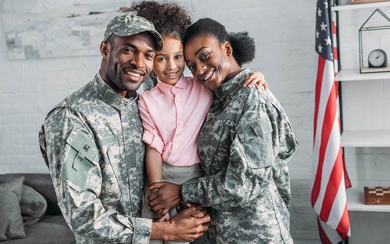 Military family smiling together by an American flag.